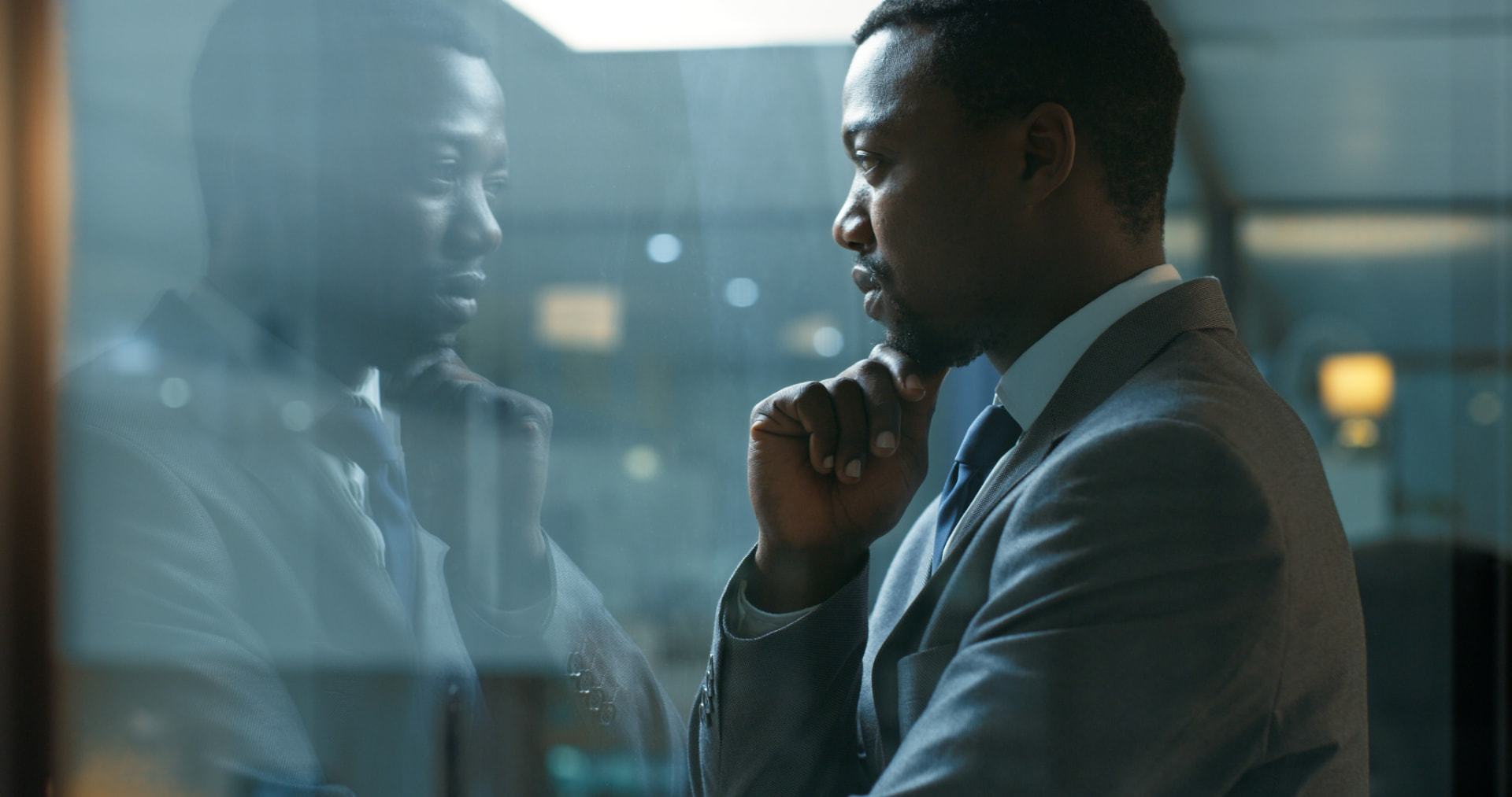 Businessman in thought reflected in an office window
